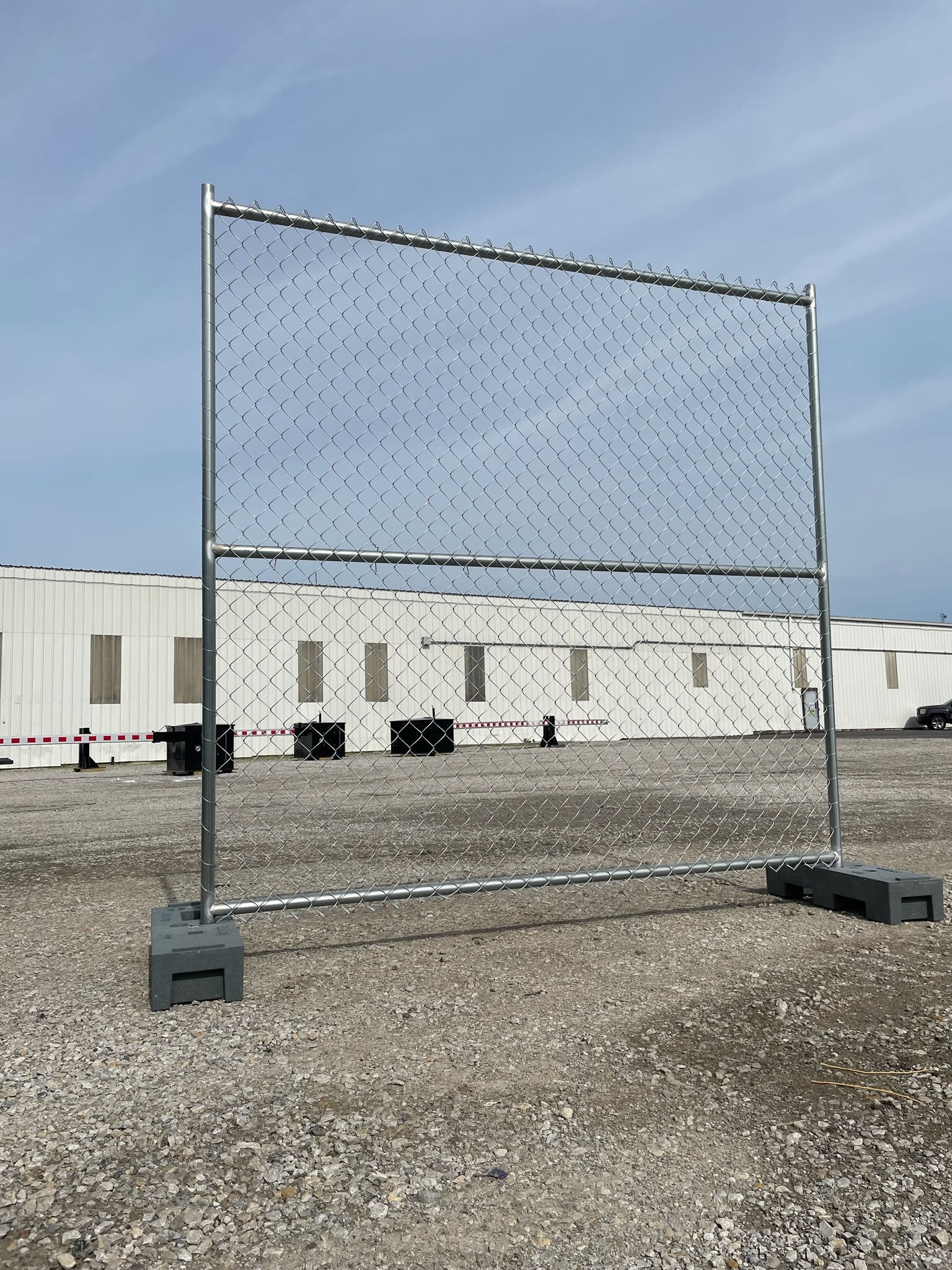 Chain link temporary fence panel with steel frame and weighted bases, ideal for construction sites and event security.